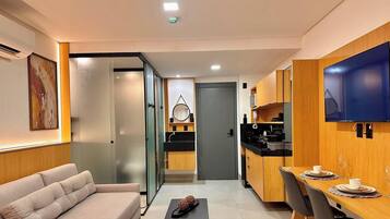 Un espace de vie compact comprenant un canapé, une kitchenette et un téléviseur à écran plat.