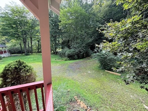 A covered patio with a view of a well-maintained garden and a small pond. - Creekfront • Pet Friendly • Sleeps 4 • Near Boone & West Jefferson (Todd)