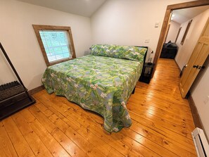 A bedroom with a bed, wooden flooring, a window with blinds, and a door. - Creekfront • Pet Friendly • Sleeps 4 • Near Boone & West Jefferson (Todd)