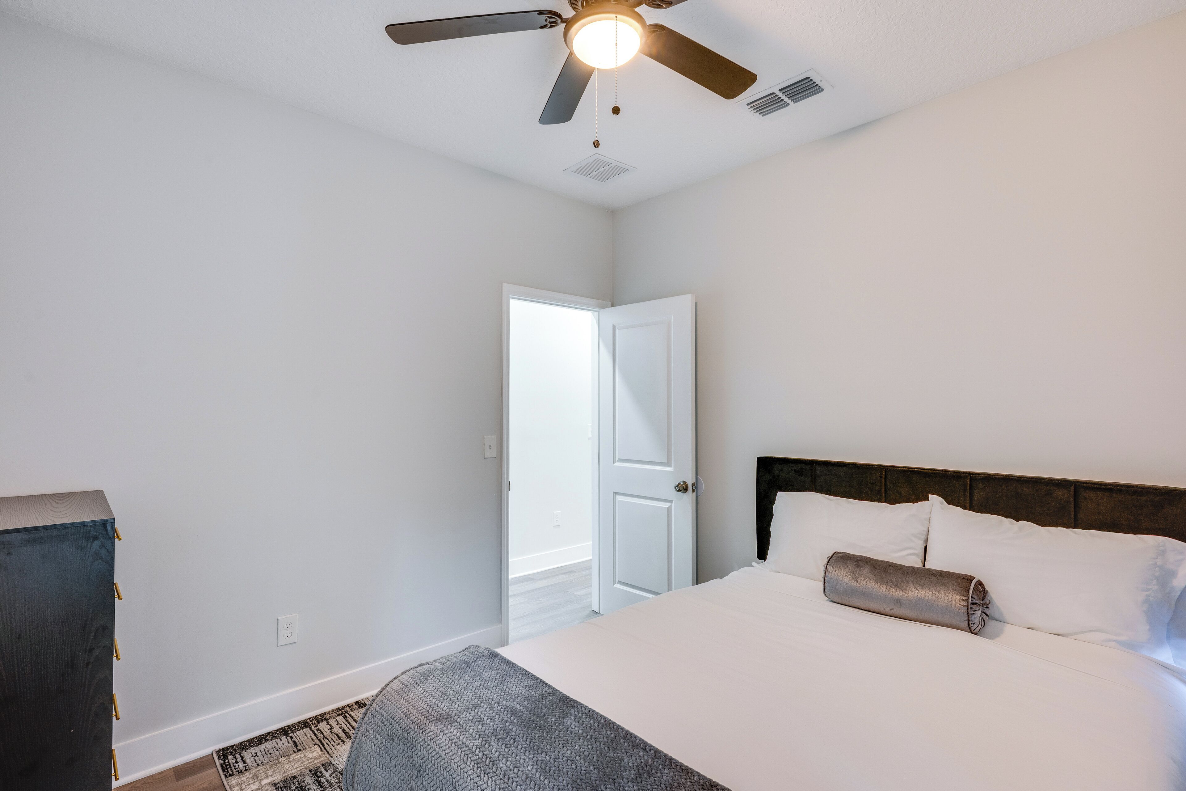 A bedroom with a bed, a ceiling fan, and a door.