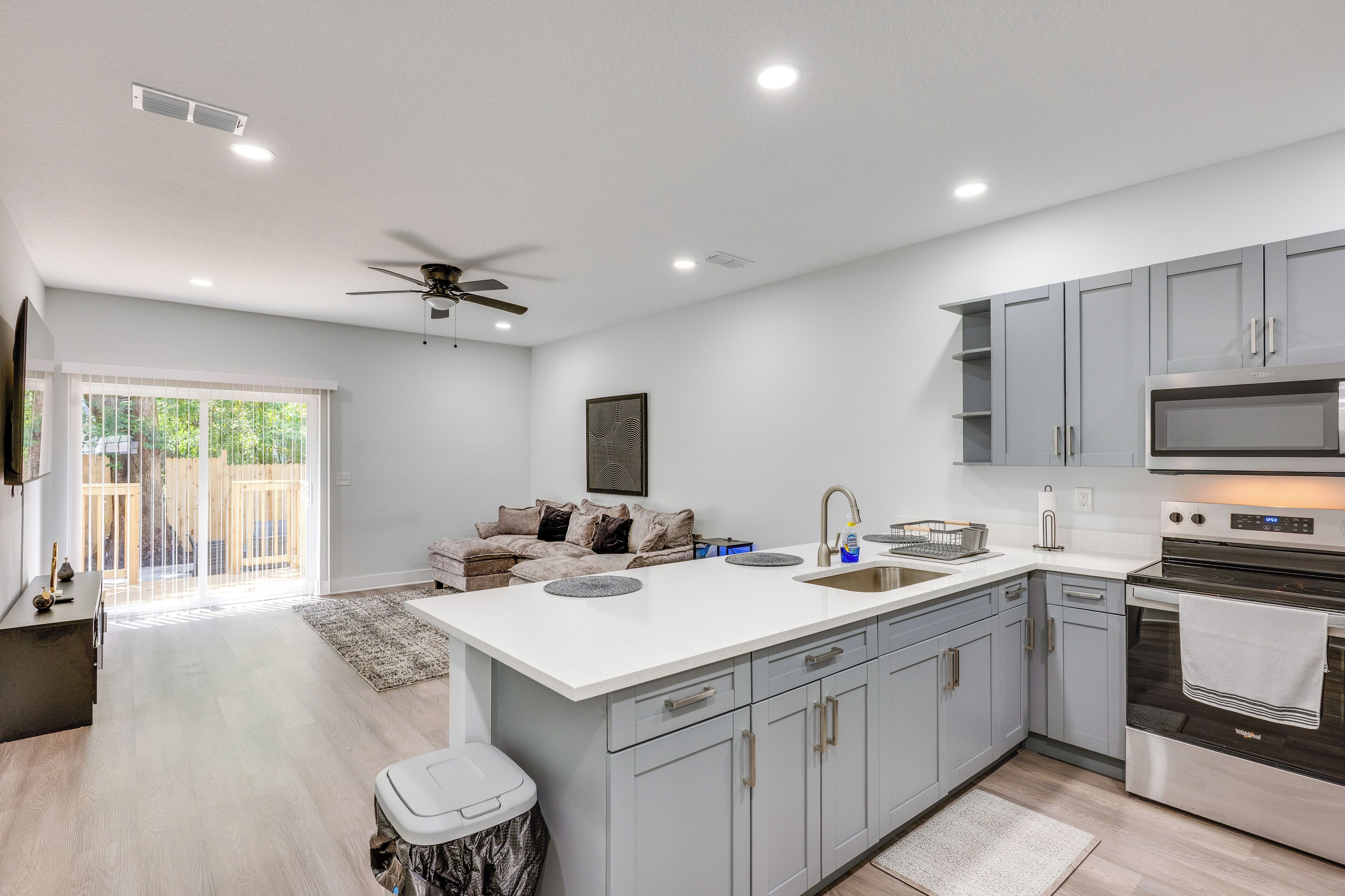 A modern kitchen with grey cabinets, a central island, and a built-in oven.