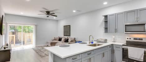 A modern kitchen with grey cabinets, a central island, and a built-in oven.