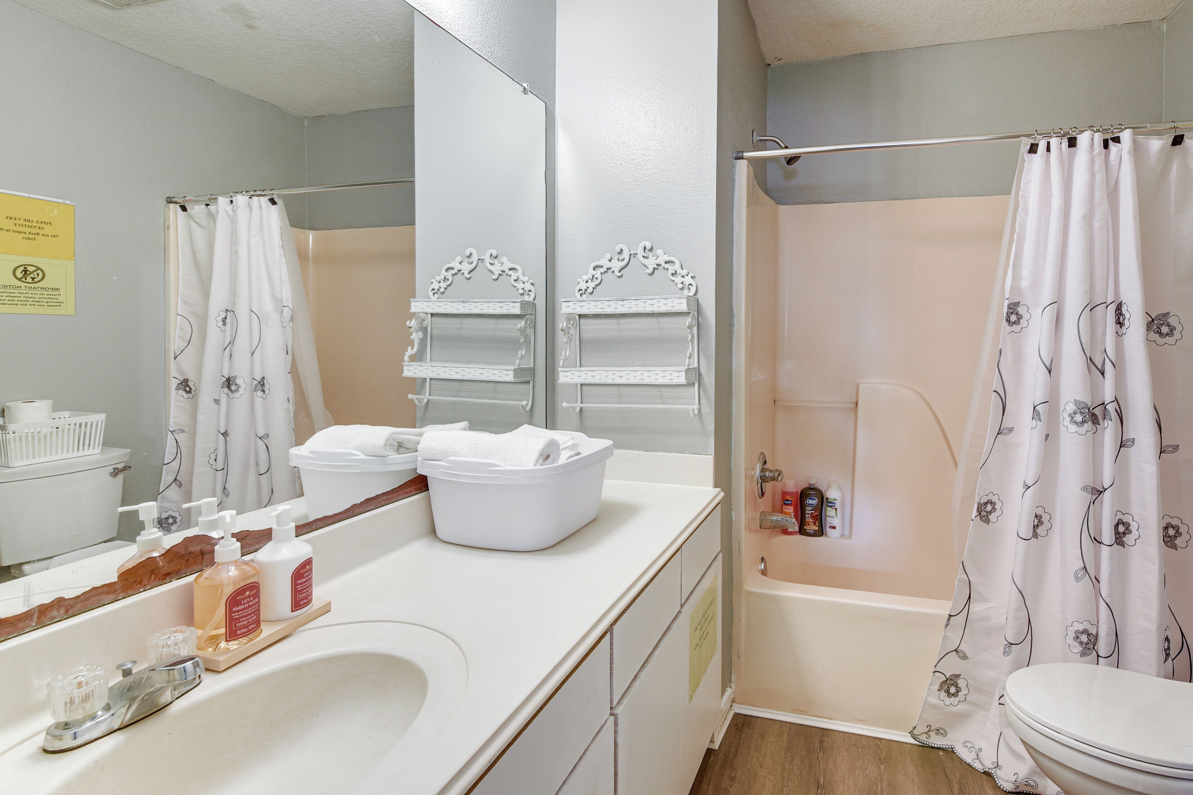 Un bagno con una vasca, un water, un lavandino con articoli da toilette e uno specchio.