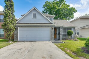 A residential house with a garage, a front door, and a small front yard with a tree and a decorative stone planter. - 2-unit Combo 10 Mi to Vintage Park & Airport! (Houston)