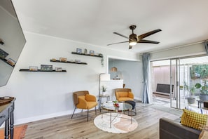 Una sala de estar moderna con un ventilador de techo, dos sillones, una mesa de centro y vistas a través de un ventanal.