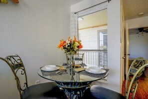 Un comedor con una mesa de vidrio, sillas de metal y un florero con flores.
