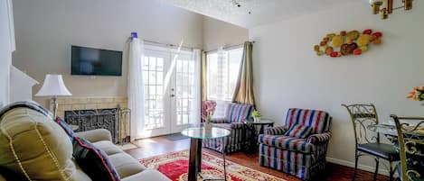 A living room with a sofa, armchairs, a TV, a ceiling fan, and a decorative wall piece.