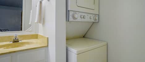 Un lavadero pequeño con lavadora, secadora y lavabo.