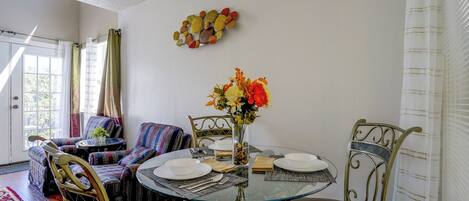 A dining area with a glass table, chairs, and a vase with flowers.