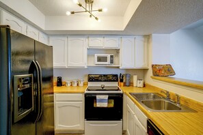 A compact kitchen with a refrigerator, stove, microwave, and sink. - Walk to Shops & Museums! Fort Worth Condo w/ Pool (Fort Worth)
