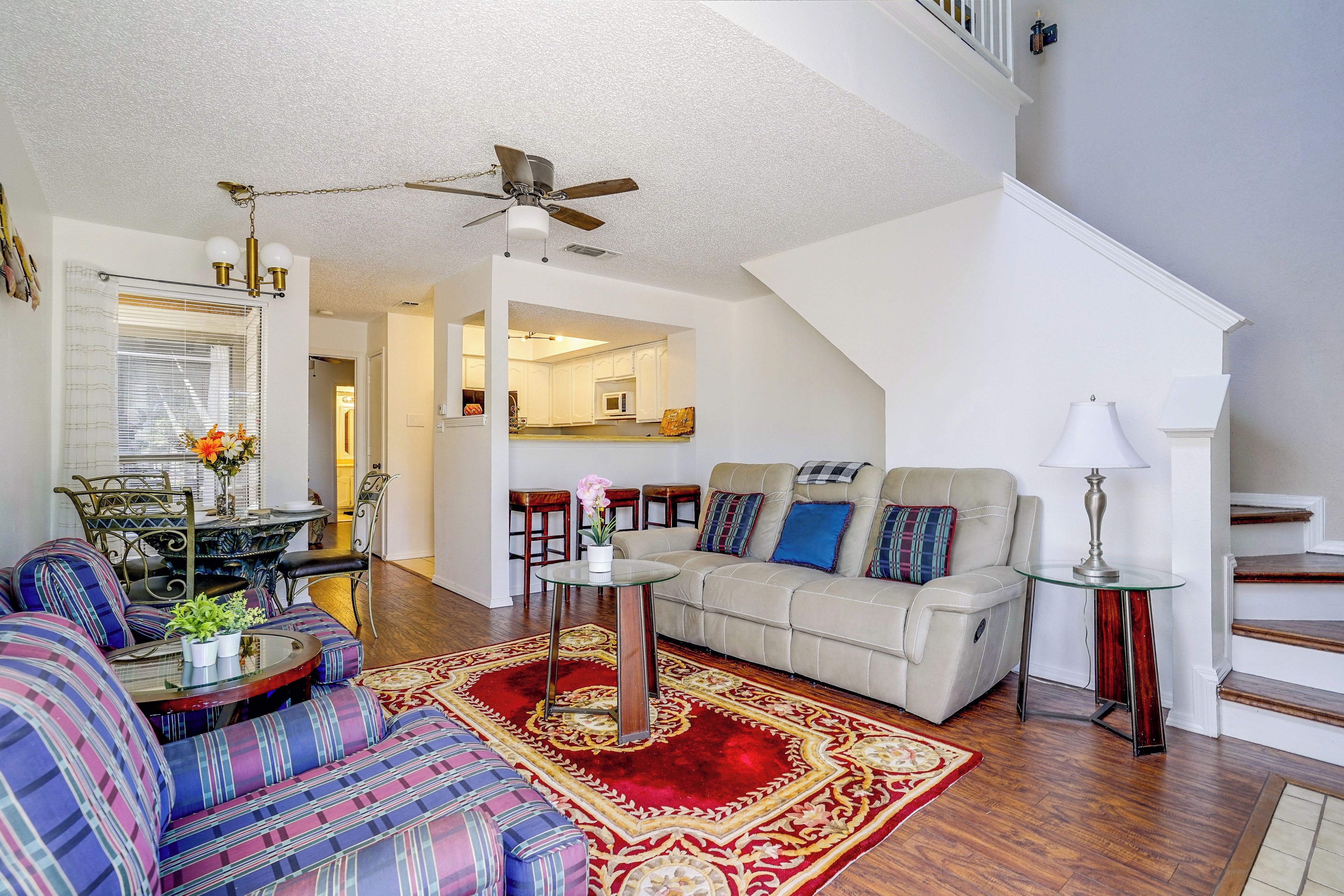 A spacious living room with a sofa, a dining area, and a staircase.