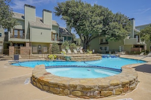 A swimming pool with a stone border, surrounded by lounge chairs and a tree. - Walk to Shops & Museums! Fort Worth Condo w/ Pool (Fort Worth)
