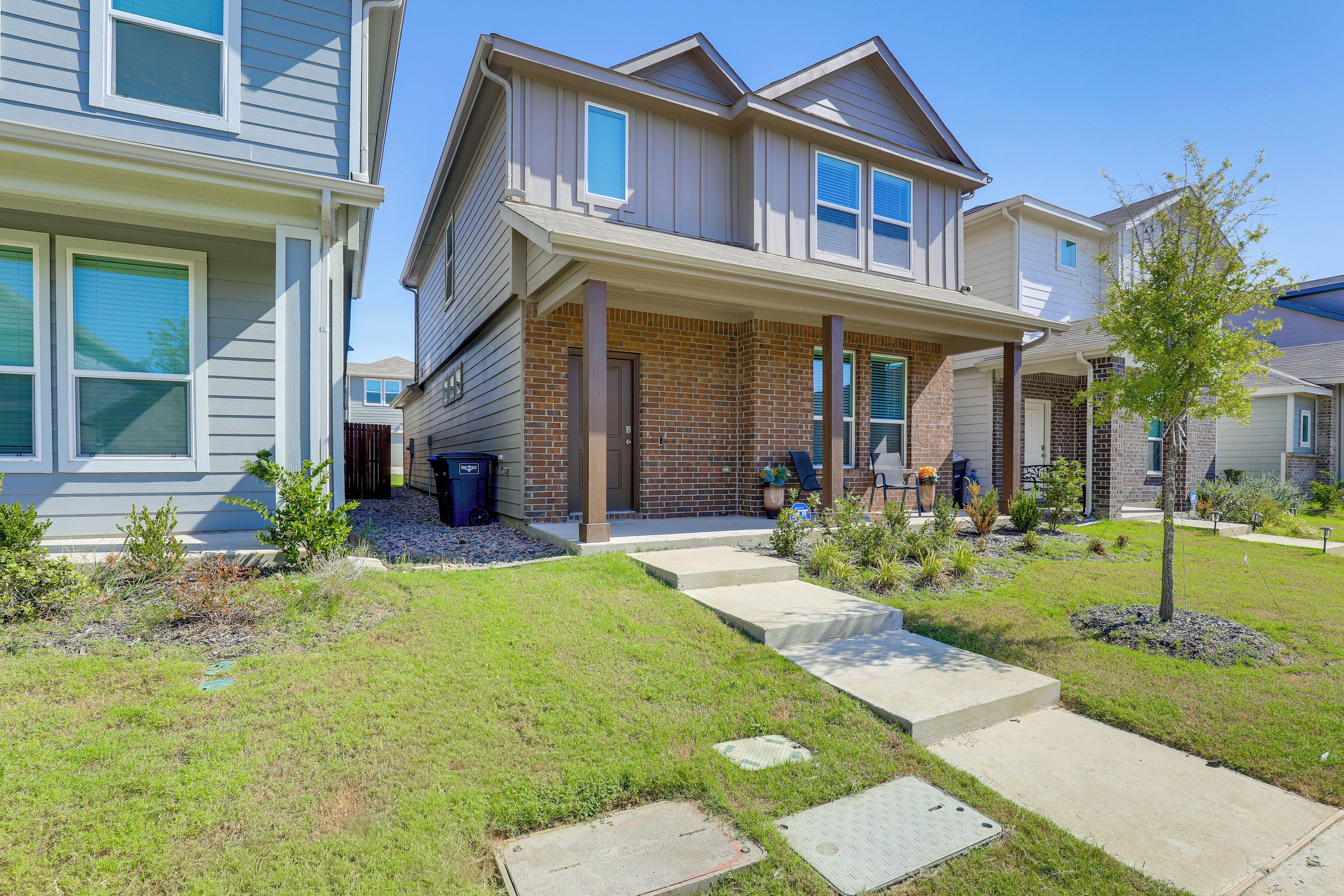 A residential building with a brick facade, a covered porch, and a well-maintained lawn.