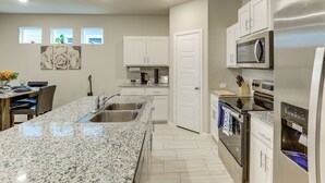 A kitchen with granite countertops, stainless steel appliances, and white cabinetry. - Family-friendly Fort Worth Home: Private Yard (Fort Worth)