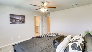 A bedroom with a bed, a ceiling fan, a door leading to another room, and a wall-mounted picture. - Family-friendly Fort Worth Home: Private Yard (Fort Worth)