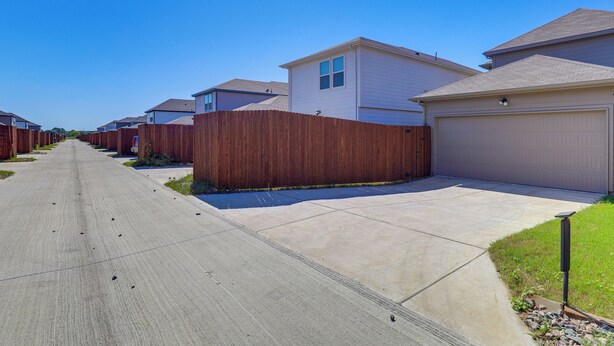 A residential street with houses, a concrete driveway, and a wooden fence. - Family-friendly Fort Worth Home: Private Yard (Fort Worth)