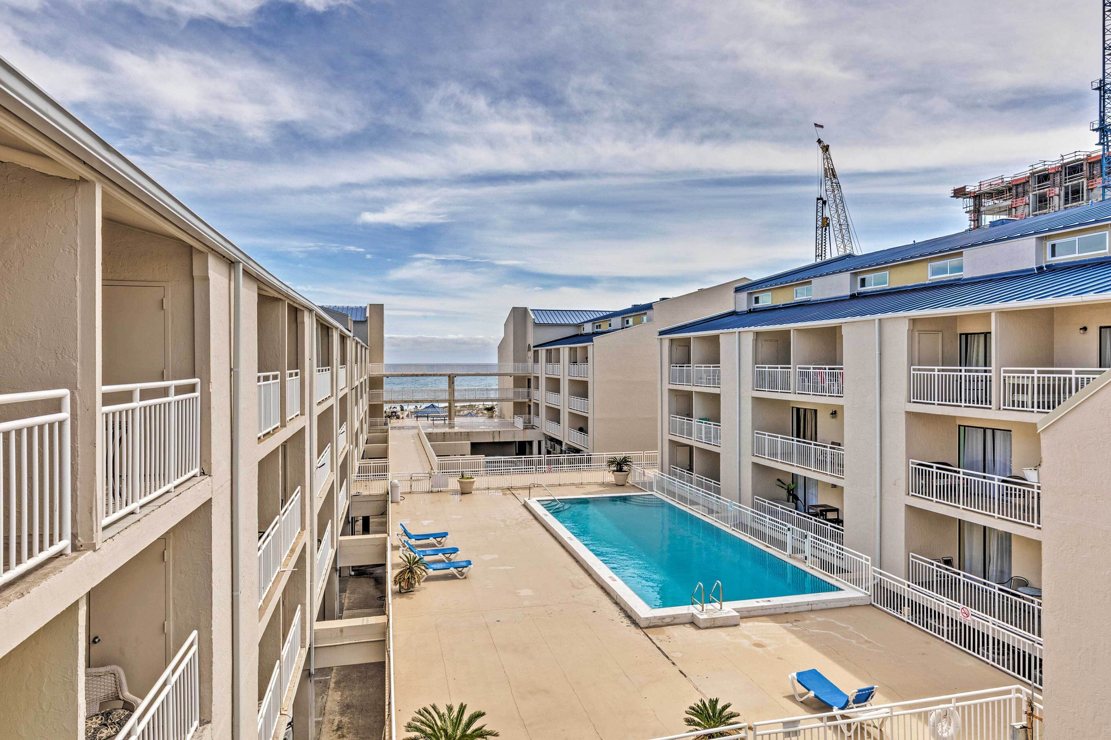 A hotel with a swimming pool, multiple balconies, and a view of the ocean.