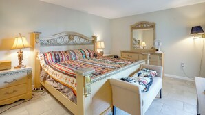 A bedroom with a bed, bedside tables, a dresser, a chair, a mirror, and a wall-mounted fan. - Steps to Golf! Extended Sun City West Getaway (Sun City West)