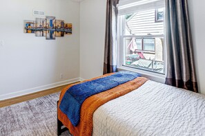 A bedroom with a bed, a window with curtains, a view of the outside, and a wall with framed artwork. - Close to Downtown Milwaukee & Mid-term Friendly! (Milwaukee)