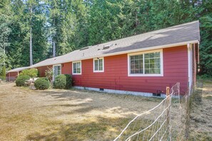 A red single-story house with a sloped roof, a front porch, and a small front yard with a fence.