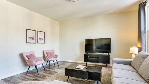 A living room with a sofa, two armchairs, a coffee table, a TV, and a lamp.