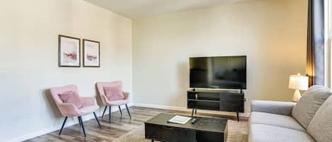 Una sala de estar con sofá, dos sillones, una mesa de centro, televisor y lámpara.