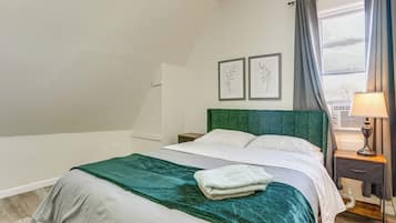 A bedroom with a bed, a nightstand, a lamp, and two framed pictures on the wall.