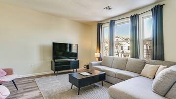 A modern living room with a flat-screen TV, a sofa, a coffee table, and a patterned rug.