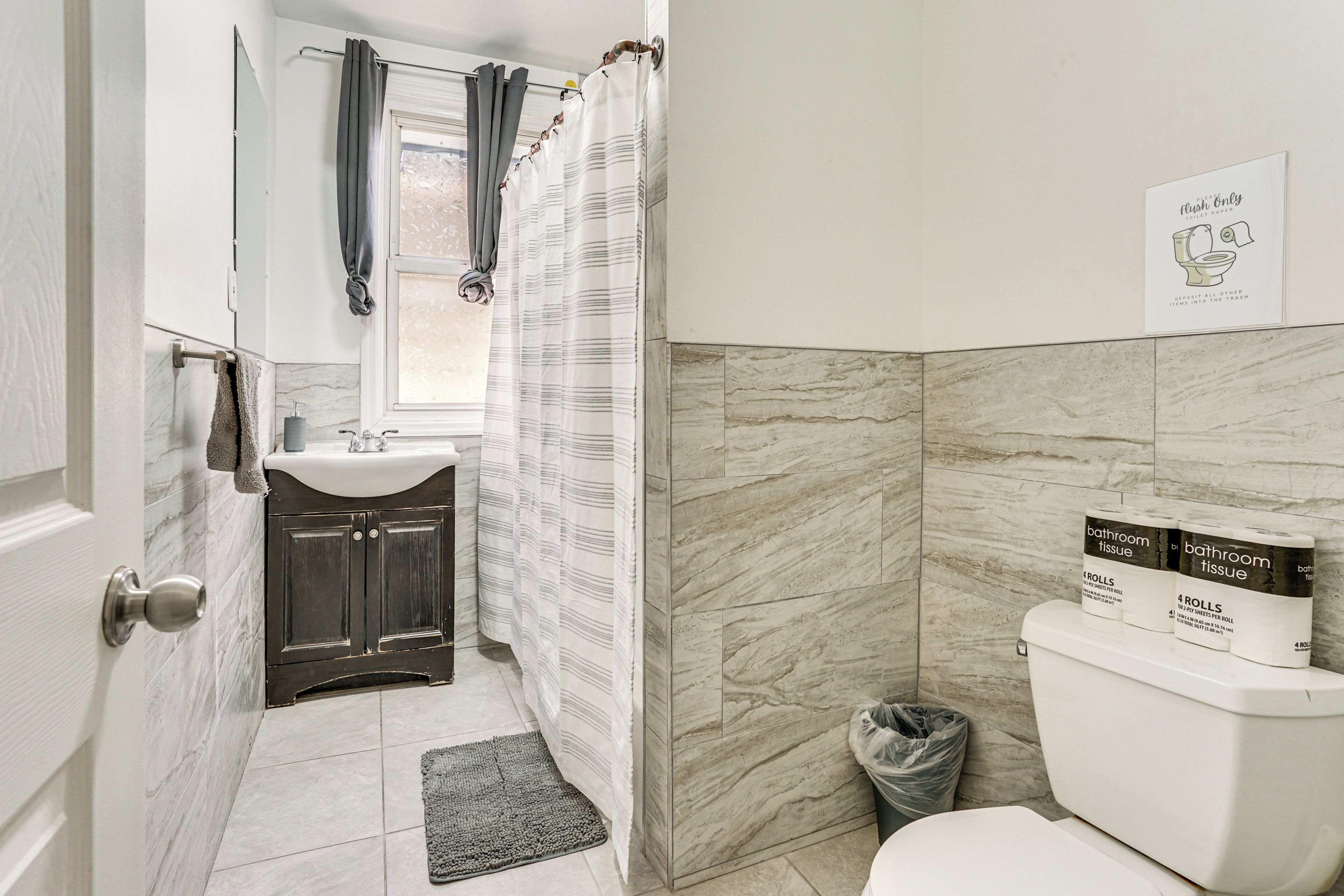 A bathroom with a toilet, a sink, a mirror, and a shower curtain.