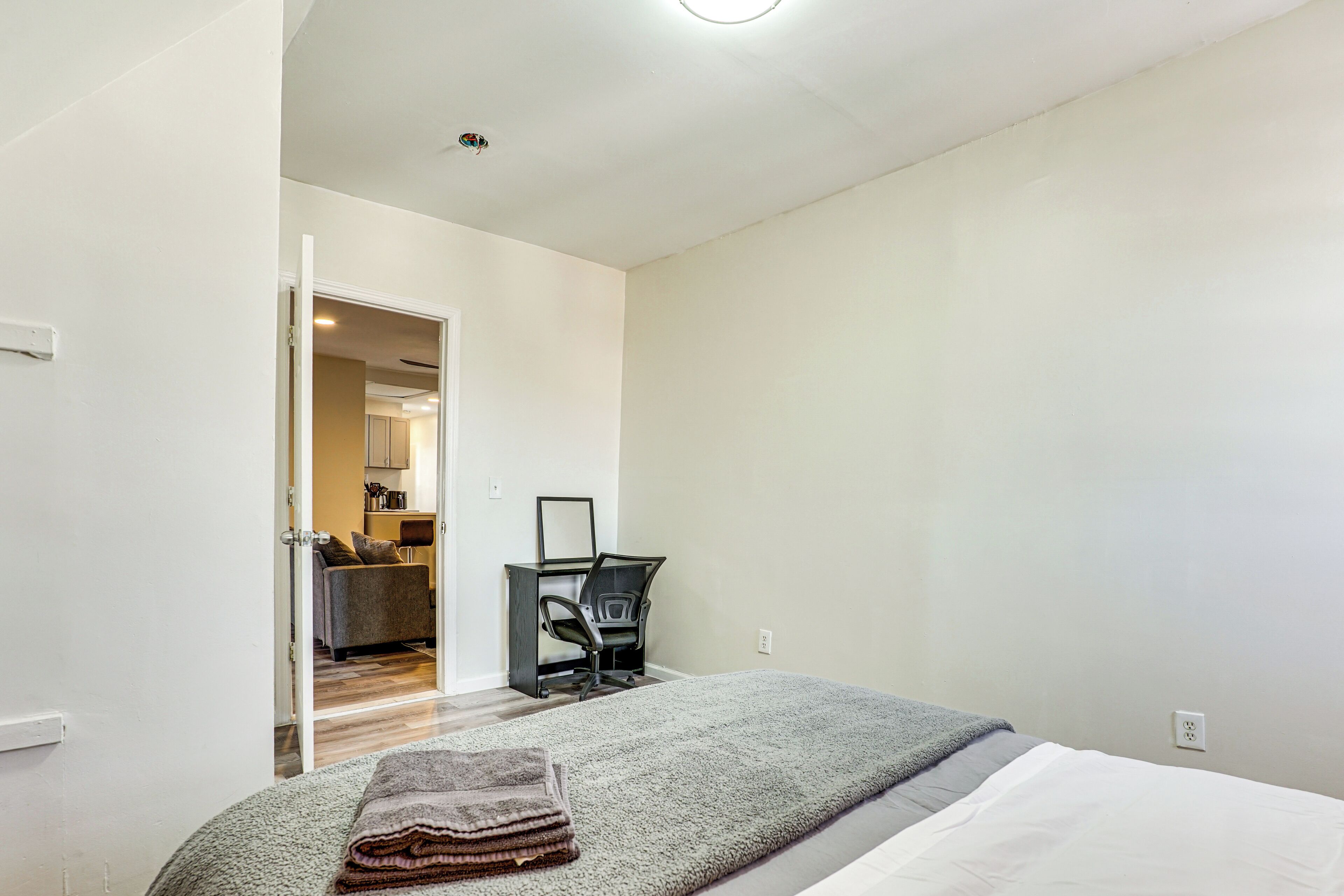 A bedroom with a bed, a desk, and a chair. There is a door leading to a bathroom.