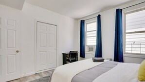 A bedroom with a bed, a desk, and a window with curtains. - Spacious Newark Duplex w/ 2 Levels & 2 Kitchens! (Newark)