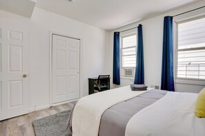 A bedroom with a bed, a desk, and a window with curtains. - Spacious Newark Duplex w/ 2 Levels & 2 Kitchens! (Newark)