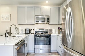 Una cocina moderna con electrodomésticos de acero inoxidable, horno empotrado y refrigerador.