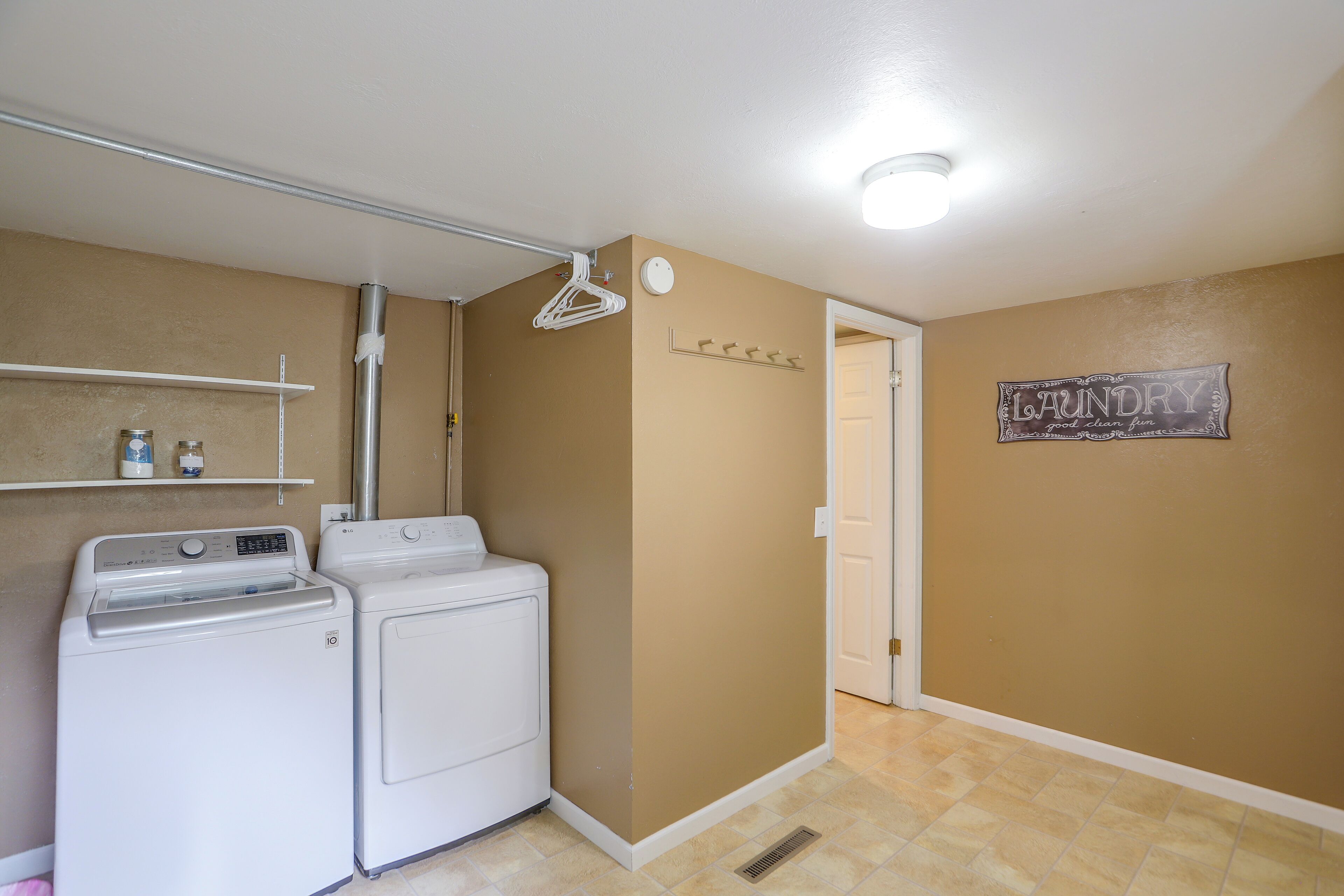 A laundry room with two white washing machines, a drying rack, and a wall-mounted coat rack.