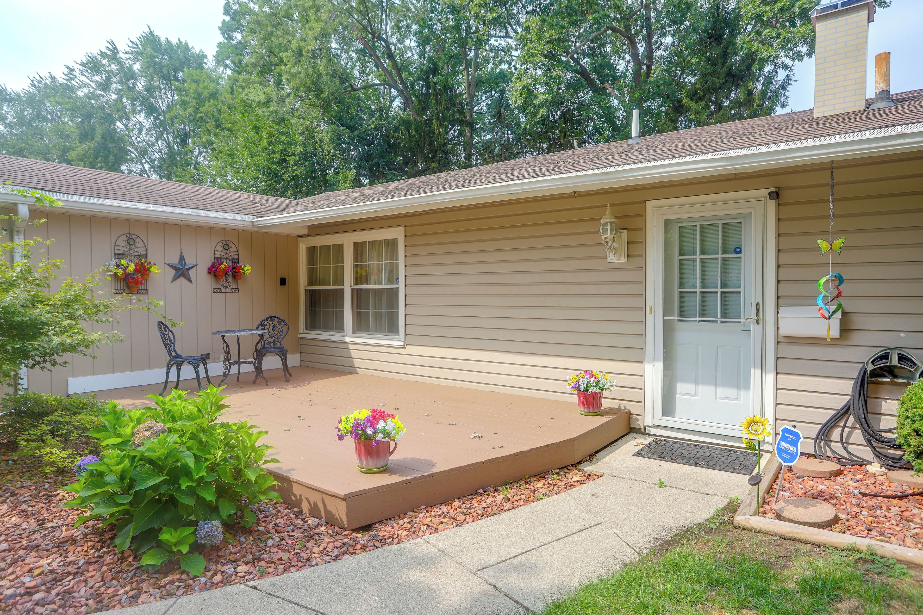 A residential building with a covered patio, outdoor seating, and a garden area.