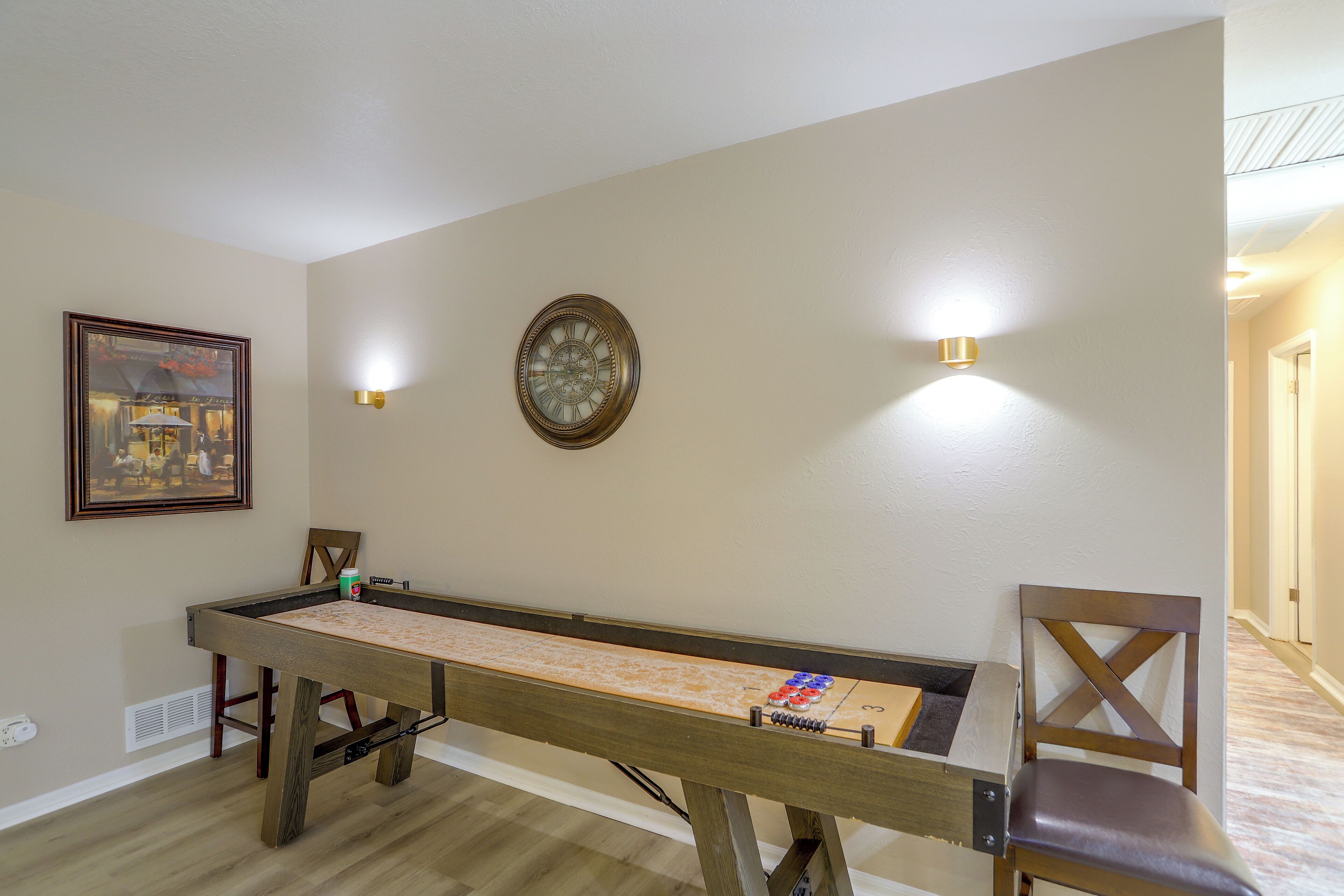 Una mesa de billar en una habitación con un cuadro enmarcado y luces fijadas a la pared.