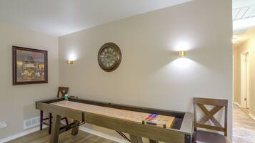 Una mesa de billar en una habitación con un cuadro enmarcado y luces fijadas a la pared.