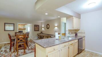 A spacious kitchen with a central island, wooden cabinets, and a built-in dishwasher.
