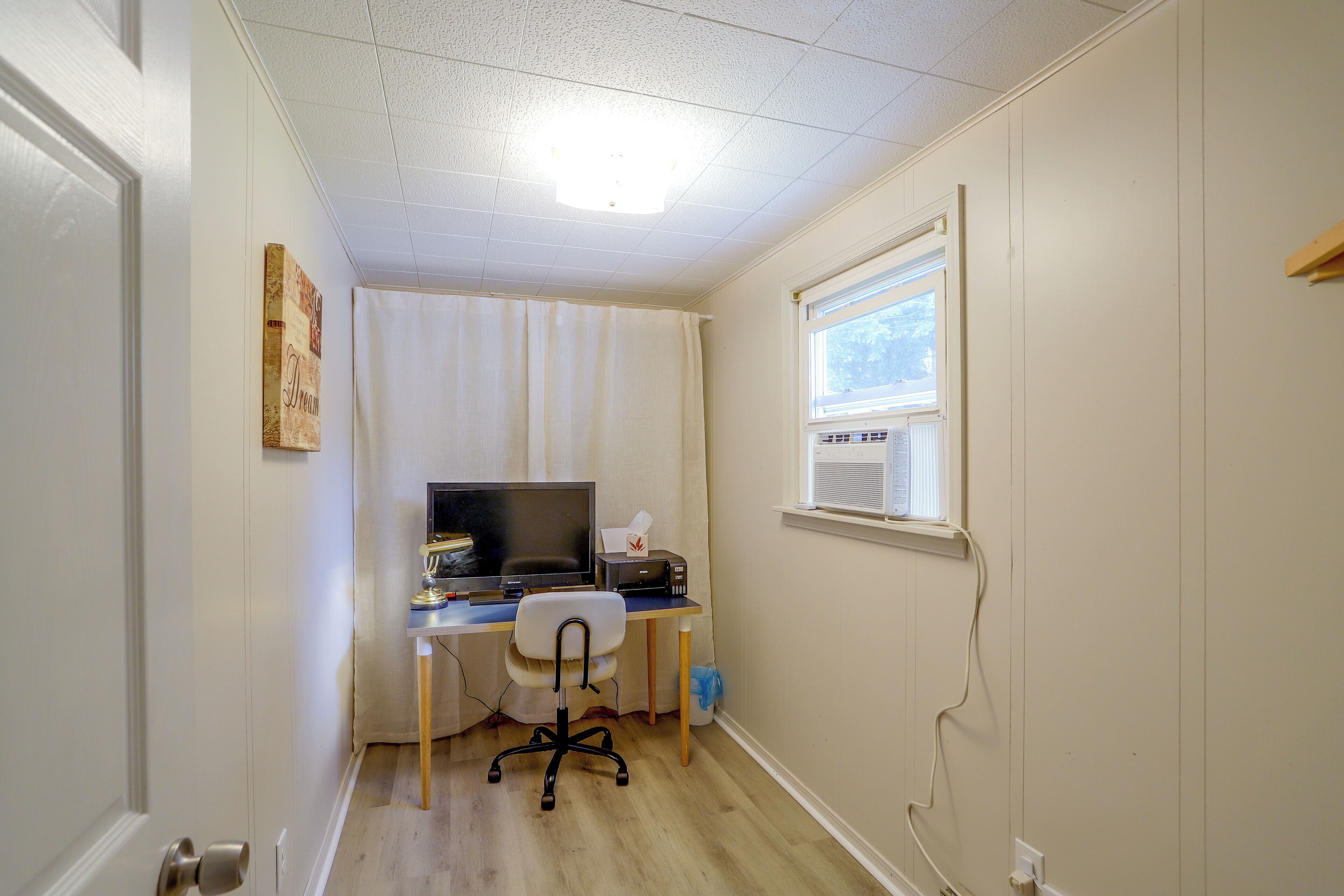 Un petit espace de bureau comprenant un bureau, une chaise, un ordinateur et une fenêtre.