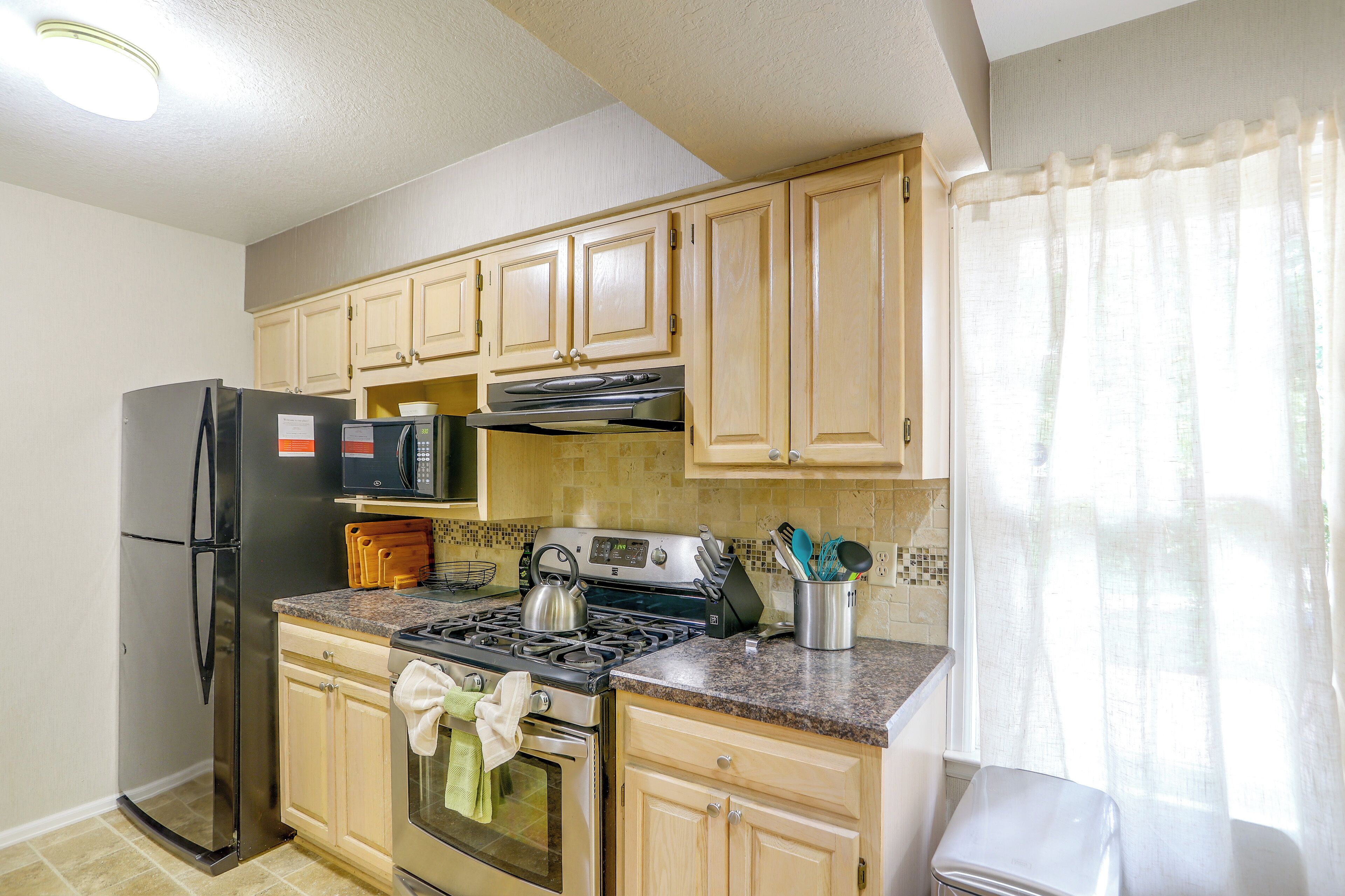 A kitchen with a refrigerator, microwave, stove, and cabinets.