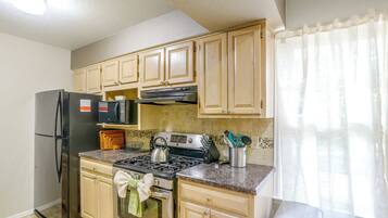 A kitchen with a refrigerator, microwave, stove, and cabinets.