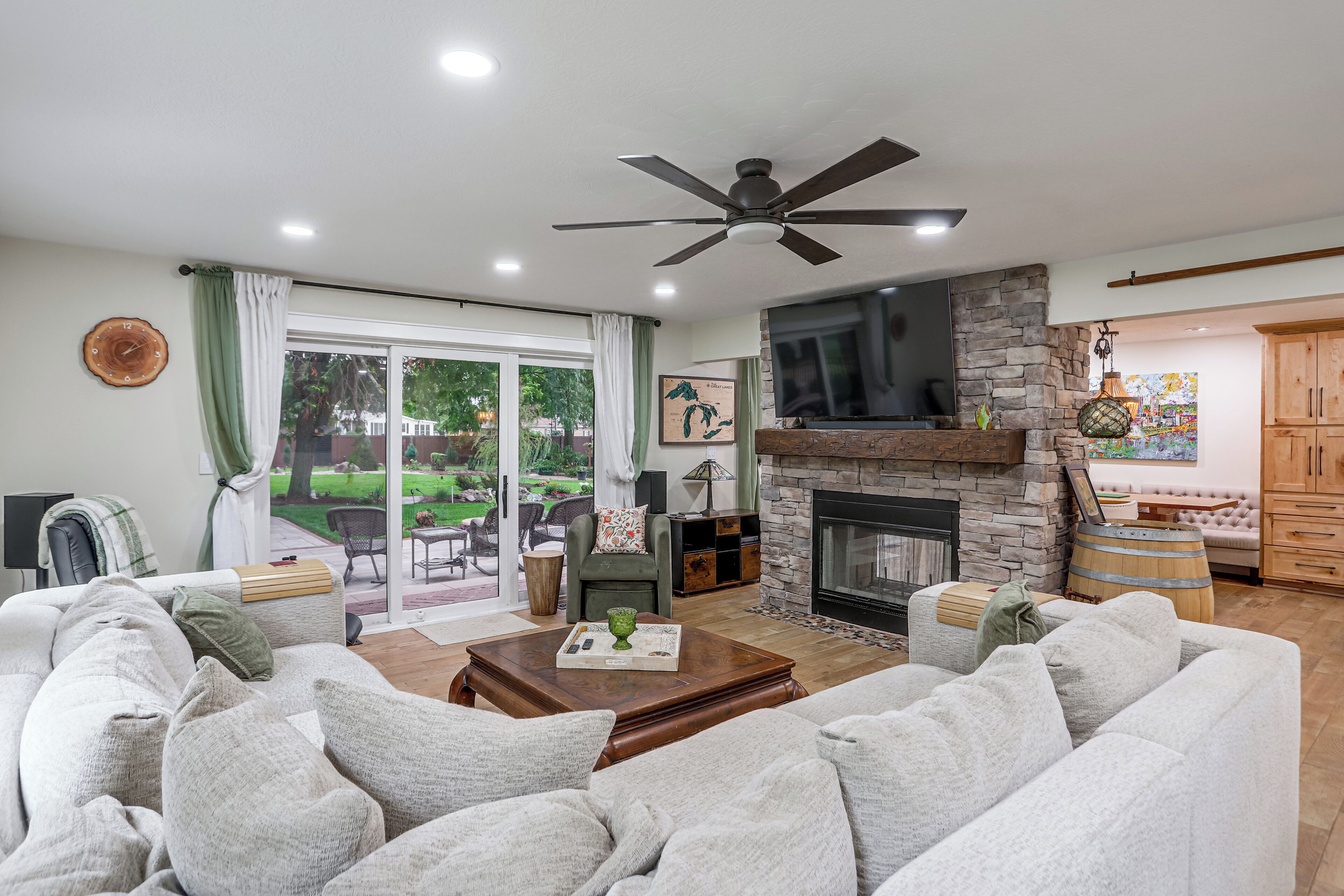 A living room with a fireplace, a ceiling fan, and a view of the outdoors.