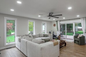 A modern living room with a sectional sofa, a coffee table, and a ceiling fan. - Stone Manor-luxury Catawba Island Home w/ Hot Tub (Port Clinton)