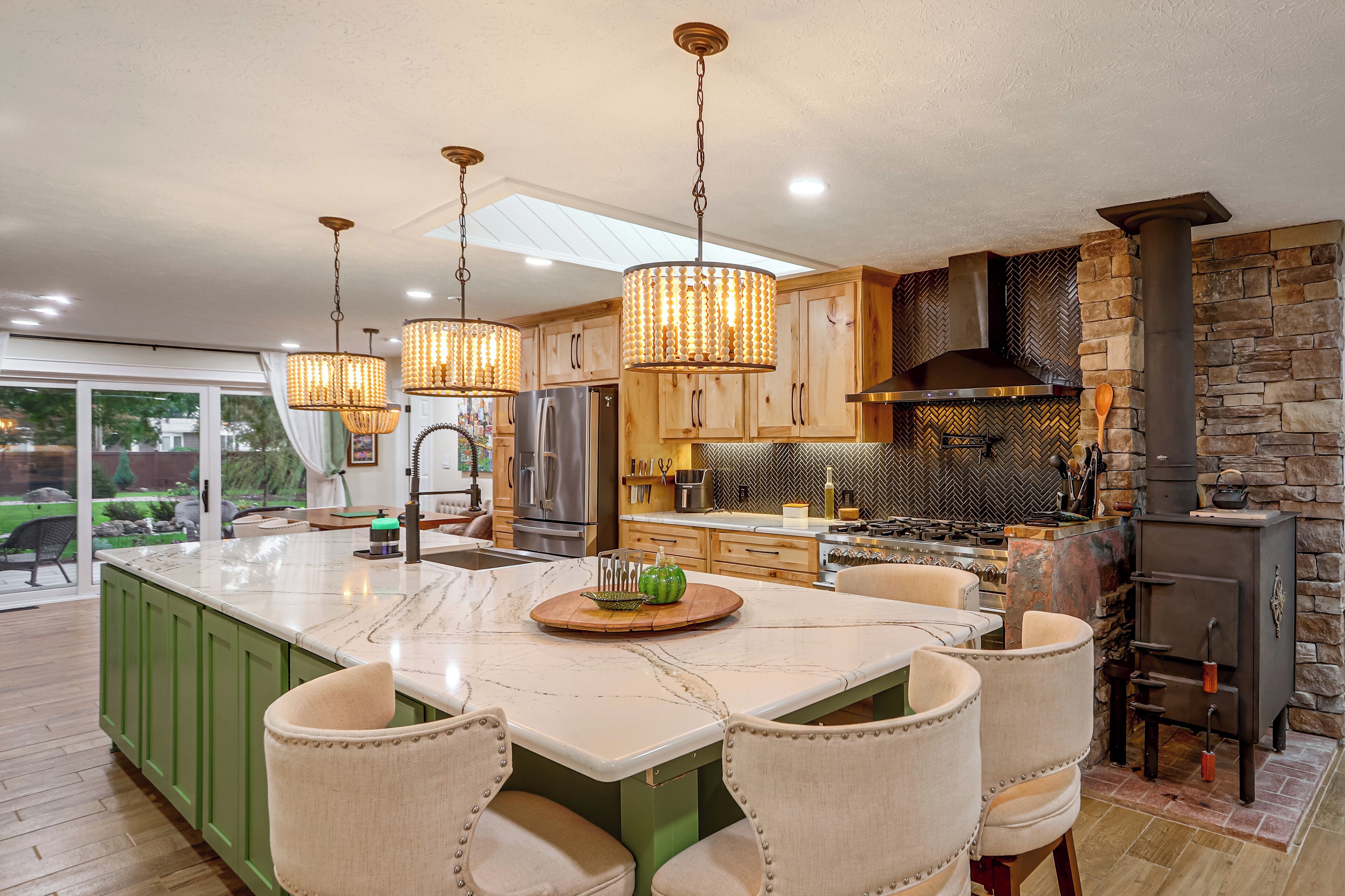 Una cocina moderna con una isla grande, iluminación colgante y una pared decorativa de piedra.