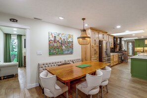 A modern kitchen with wooden cabinets, a dining table with chairs, and a pendant light. - Stone Manor-luxury Catawba Island Home w/ Hot Tub (Port Clinton)