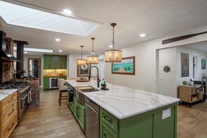 A modern kitchen with a large island, green cabinets, and pendant lighting. - Stone Manor-luxury Catawba Island Home w/ Hot Tub (Port Clinton)