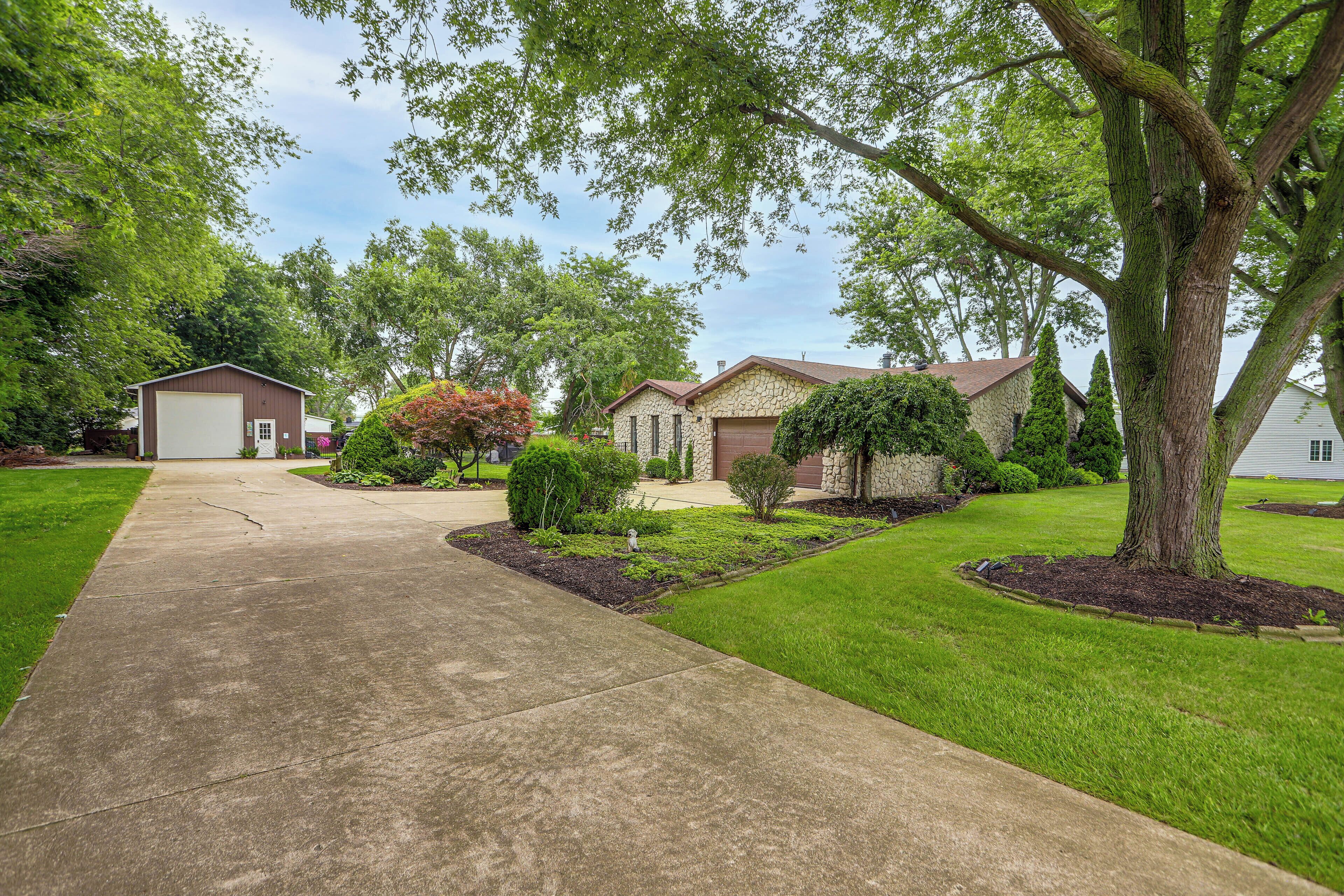 A residential area with a driveway leading to a house with a stone facade.