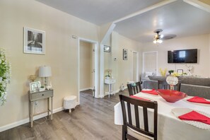 A spacious living area with a dining table, chairs, a television, and a hallway leading to another room. - Sunny Hemet Escape w/ Covered Porch & Fire Pit (Hemet)