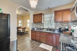 A modern kitchen with wooden cabinets, a granite countertop, and a built-in stove. - Sunny Hemet Escape w/ Covered Porch & Fire Pit (Hemet)