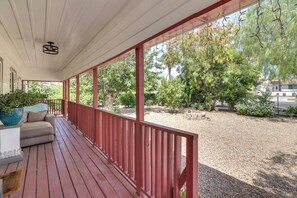 A covered porch with a red railing, a beige sofa, and a potted plant. - Sunny Hemet Escape w/ Covered Porch & Fire Pit (Hemet)